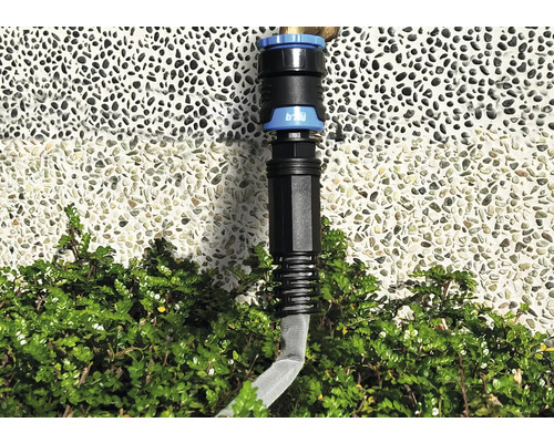 Spojka zahradní hadice před zdí a keři