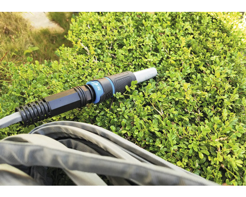 Zahradní hadice s konektorem na zelené rostlině