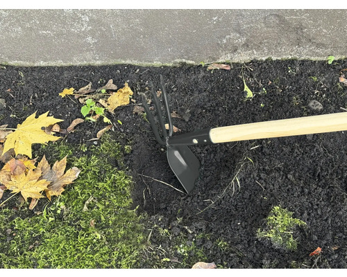 Motyka se dřevěnou násadou v záhonu