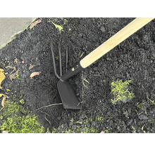 Zahradní nářadí s dřevěnou násadou a kovovou hlavou v zemi