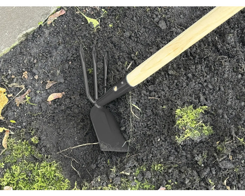 Zahradní nářadí s dřevěnou násadou a kovovou hlavou v zemi