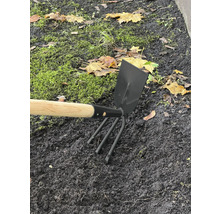 Zahradní nářadí s dřevěnou násadou a trojzubými hroty v záhonu