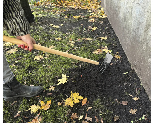 Práce na zahradě s kombinovanou motykou pro zpracování půdy