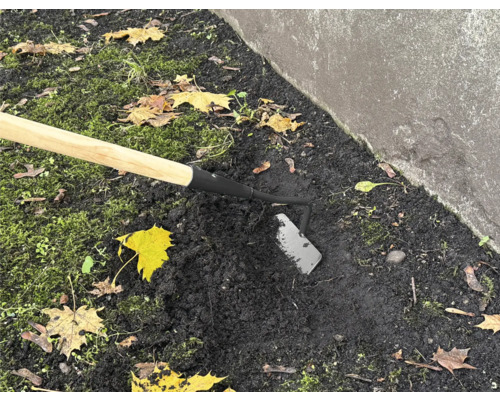 Zahradní motyka s dřevěnou násadou používaná v zahradní půdě.