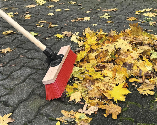 Koště zametá podzimní listí na dlažebních kostkách