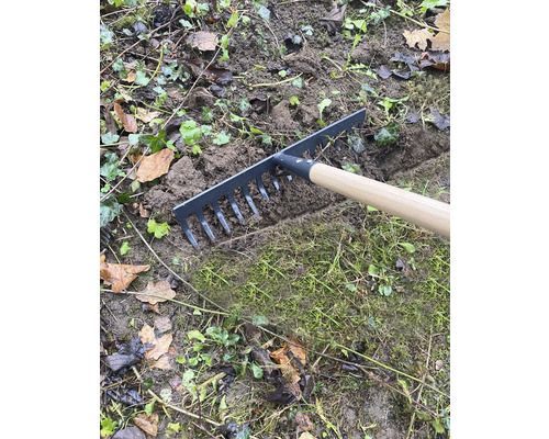 Zahradní hrábě s dřevěnou rukojetí při zarovnávání zeminy