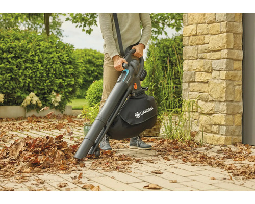 Osoba používá akumulátorový vysavač listí Gardena na zahradě k sběru listí.