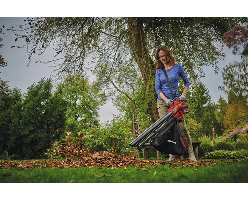 Žena používá na zahradě vysavač listí k odstraňování listí.