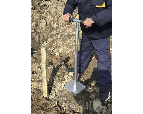 Muž hutní půdu ručním pěchovadlem