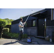 Muž čistí střechu domu vysokotlakým čističem