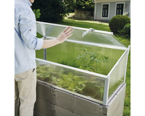 Vyvýšený záhon s pařeništěm a osobou v zahradě.