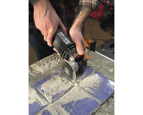 Osoba používá multifunkční nástroj k řezání dlaždic.