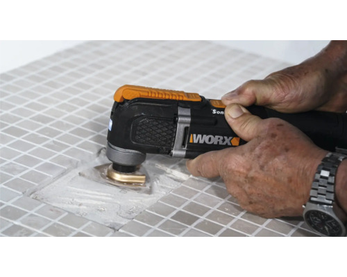 Detailní pohled na osobu, která opracovává dlaždice multifunkčním nástrojem, značka Worx