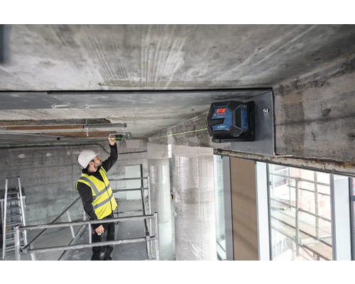 Stavební dělník používá čárový laser pro vyrovnání na staveništi.