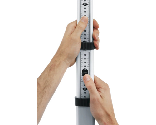 Dvě ruce drží nivelační lať pro měření výšky.