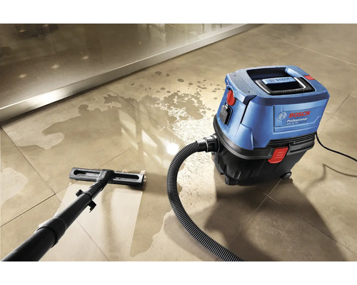 Modrý a černý mokro-suchý vysavač Bosch čistí dlážděnou podlahu