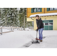 Muž odklízí sníh před domem pomocí sněhové frézy