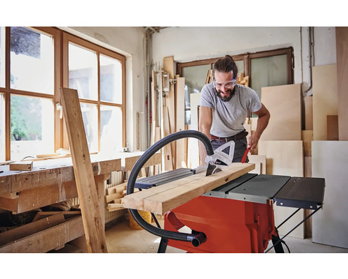 Muž řeže dřevo stolní pilou v dílně