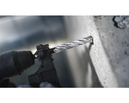 Detailní záběr vrtačky s vrtákem do betonu vrtající do betonu