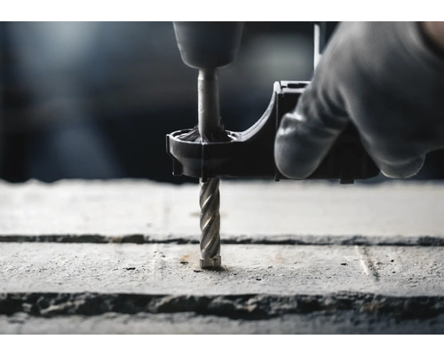 Detailní záběr vrtačky vrtající beton kamenným vrtákem