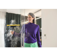 Žena čistí skleněnou stěnu parním čističem