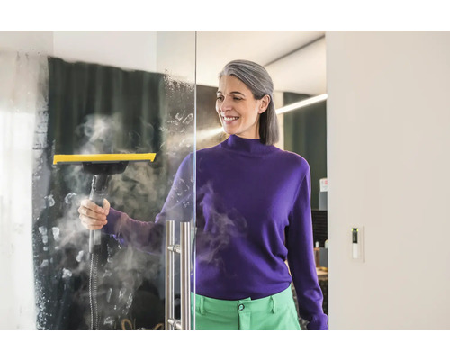 Žena čistí skleněnou stěnu parním čističem