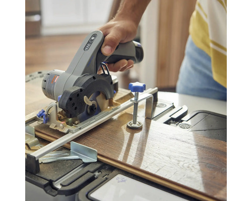 Osoba řeže dřevěnou desku ruční kotoučovou pilou.