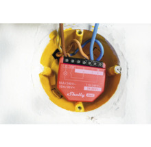 Detailní záběr relé Shelly Gen3 v žluté zapuštěné krabici s elektrickými vodiči.