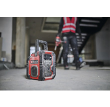 Stavební rádio značky Einhell stojí na podlaze hrubé stavby.