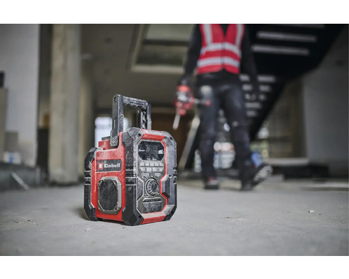 Stavební rádio značky Einhell stojí na podlaze hrubé stavby.