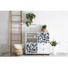 Pohled do pokoje s bílou úložnou skříní, žebříkem a pokojovými rostlinami před bílou cihlovou zdí