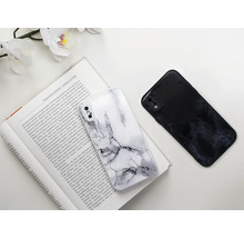 Dva kryty na mobilní telefony s mramorovým vzorem leží na otevřené knize.