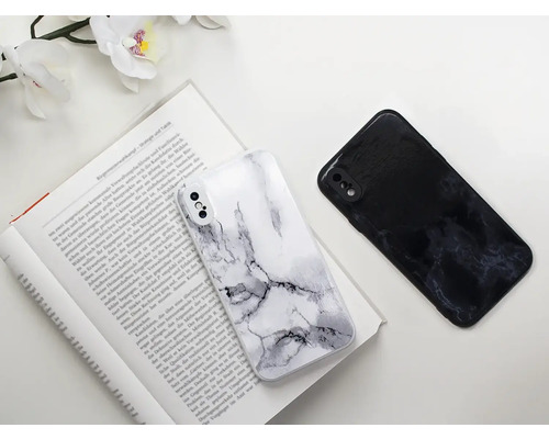 Dva kryty na mobilní telefony s mramorovým vzorem leží na otevřené knize.