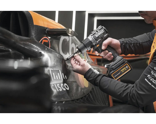 Mechanik upevňuje součást na závodní auto pomocí akumulátorového šroubováku.