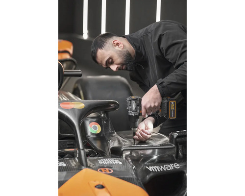 Muž používá akumulátorový vrtací šroubovák DeWalt na voze Formule 1.