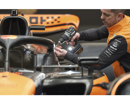 Mechanik používá akumulátorový šroubovák na závodním autě.