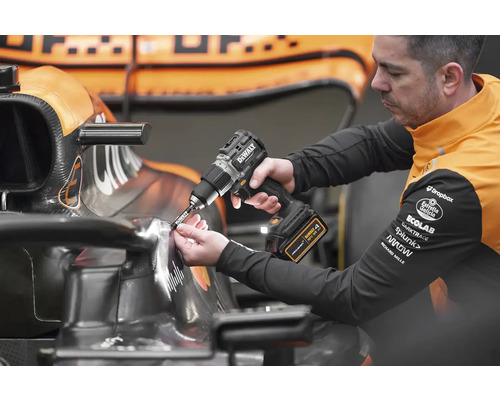Muž používá akumulátorový šroubovák na závodním autě.