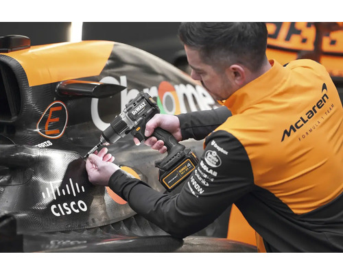 Mechanik používá akumulátorový vrtací šroubovák DeWalt na závodním autě.