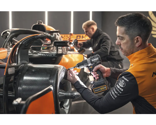 Muž montuje kolo na závodní auto pomocí akumulátorového šroubováku.