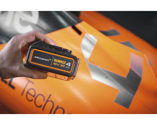 Baterie Dewalt 18 V XR 4 Ah v ruce před vozem formule 1 McLaren.