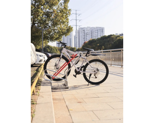 Jízdní kolo zaparkované ve stojanu na kola před městským pozadím