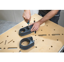 Osoba montuje odsávací nástavec pomocí šroubováku na pracovní stůl