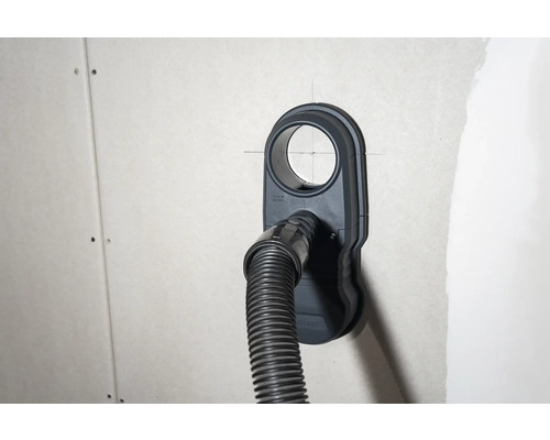 Zásuvka pro připojení vysavače s připojenou hadicí vysavače na stěně