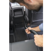 Osoba čistí interiér auta vysavačem.