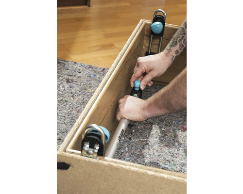 Muž upevňuje montážní úhelník Wolfcraft do dřevěné bedny