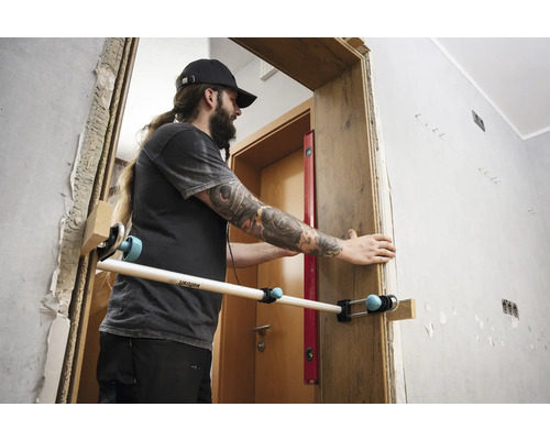 Muž montuje zárubeň pomocí montážního nástroje