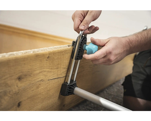 Uživatel upevňuje dřevěnou desku montážním nástrojem.