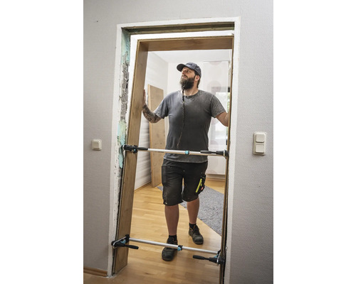 Muž montuje dveře pomocí rozpěrky dveří.