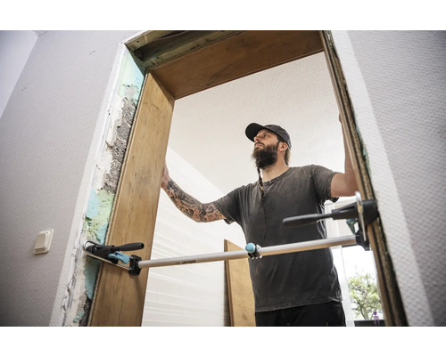 Řemeslník montuje dřevěné dveřní zárubně pomocí latě