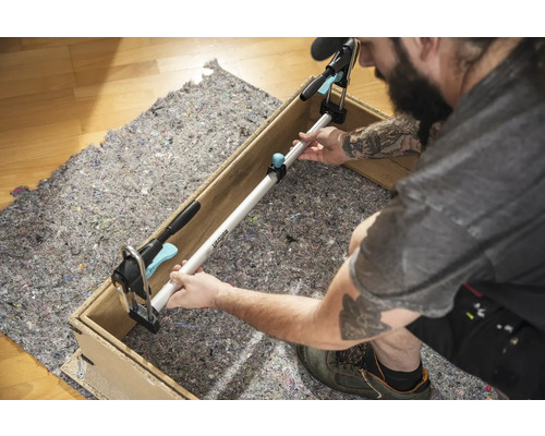 Řemeslník upevňuje rozpěrnou tyč mezi dvě strany dřevěného rámu